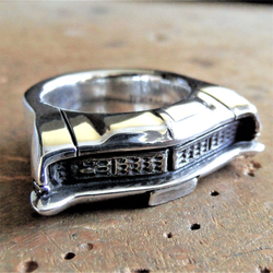 Nahaufnahme eines silbernen Rings mit der gravierten Frontansicht eines Ford Galaxie 1968, detailreich und poliert