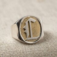 Handgefertigter Initialenring aus 925 Sterling Silber mit goldfarbener Ringtafel und erhabenem Monogramm auf Leinenstoff