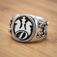 Handgefertigter massiver Initialenring aus 925 Sterling Silber mit Wappenmotiv, Monogramm und ornamentierten Seiten auf Holzuntergrund