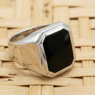 Handgefertigter Onyx Siegelring aus 925 Sterling Silber mit schwarzem Stein und massiver Ringschiene auf hellem Flechtuntergrund