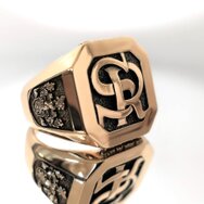 Exklusiver Siegelring aus 750 Roségold mit erhabenem Monogramm, seitlichem Wappenmotiv und dunkler strukturierter Ringplatte