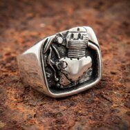 Massiver Silberring mit plastischem Norton Motorrad Motor, geschwärztem Hintergrund und detailreicher Mechanik auf rostigem Metall