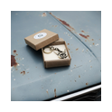 V8 Schlüsselanhänger Messing in Geschenkbox auf blauer, verrosteter Motorhaube.