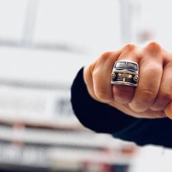 Handgefertigter Ring aus Sterling Silber, inspiriert von der Front eines 1968er Dodge A-Modells, mit dem Oldtimer unscharf im Hintergrund
