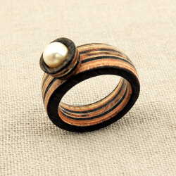 Handgefertigter mehrschichtiger Holzring mit natürlicher Streifenmaserung aus Edelhölzern, verziert mit weißer Süßwasserperle auf Leinenstoff