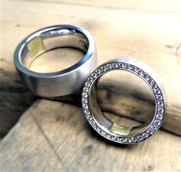 Zwei Eheringe aus 585er Weißgold, im Anschnitt sieht man die Innenschiene mit eingelegtem Fingerabdruck aus Gold