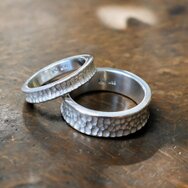 Zwei handgefertigte Trauringe mit Hammerschlag aus 925 Sterling Silber auf einer Goldschmiedewerkbank